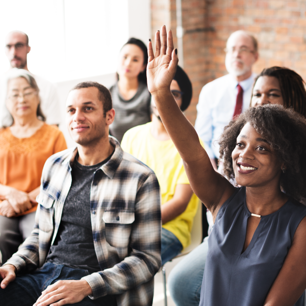 Woman in a group meeting with her hand raised